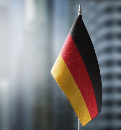 A small flag of Germany on the background of a blurred background A small flag of Germany on the background of an urban abstract blurred background.